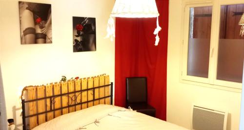 une chambre avec un lit et un rideau rouge dans l'établissement Maison de village - triangle NIMES - UZES - ALES, à Moussac