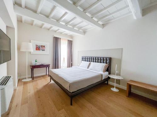 a white room with a bed and a television at Suite Greve in Chianti in Greve in Chianti