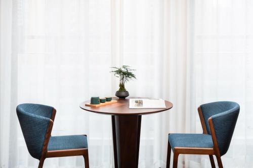 a table with two chairs and a plant on it at SSAW Boutique Hotel Foshan Qiandeng Lake in Foshan