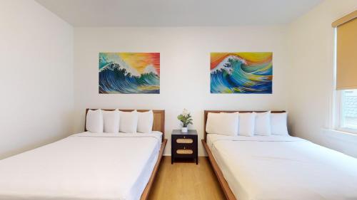 two beds in a room with paintings on the wall at The Cove in Ocean City