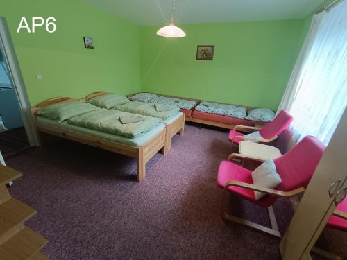 Habitación con 2 camas y sillas. en Apartmány Eva en Batňovice