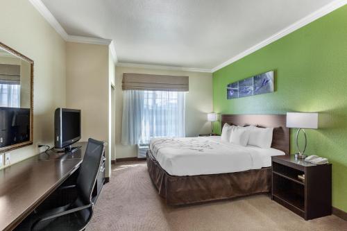 a hotel room with a bed and a flat screen tv at Sleep Inn & Suites Hewitt - South Waco in Hewitt
