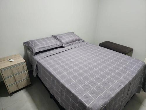 a bed with two pillows and a night stand in a bedroom at Casa Temporada Terra Nova in Uberaba