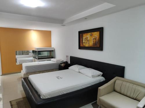 a room with three beds and a couch and a tv at Hotel Veneza in Itabuna