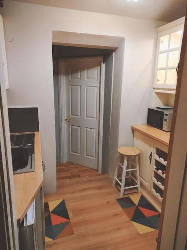 a room with a kitchen with a door and a stool at Hidden Hearts Apartment in Roscrea