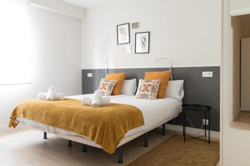 Schlafzimmer mit einem Bett mit orangefarbenen und weißen Kissen in der Unterkunft BILBAO ARGIA in Bilbao