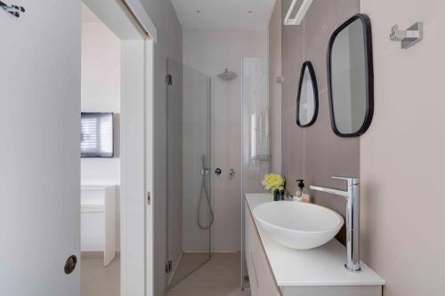 a white bathroom with a sink and a mirror at Ella SR by TLV2rent in Tel Aviv