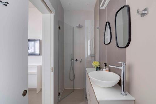 Un baño blanco con lavabo y espejo. en Ella SR by TLV2rent, en Tel Aviv