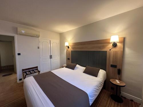 ein Schlafzimmer mit einem großen weißen Bett und einem Tisch in der Unterkunft The Originals City, Hôtel Napoléon, La Roche-sur-Yon (Inter-Hotel) in La Roche-sur-Yon
