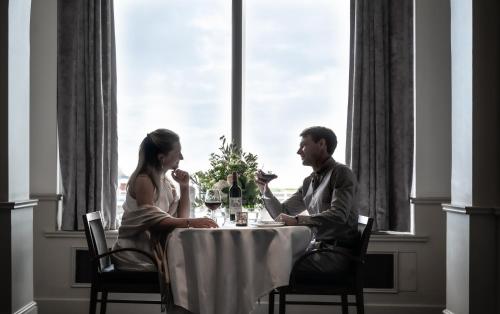 a man and woman sitting at a table in front of a window at Grand Jersey Hotel and Spa in Saint Helier Jersey