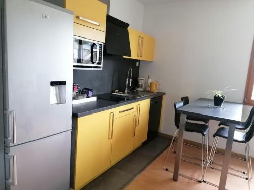 une cuisine avec un réfrigérateur blanc et une table dans l'établissement Maison calme, près du puy du fou, à La Gaubretière