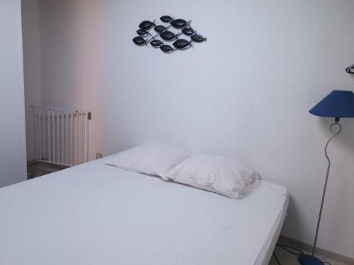 - une chambre avec un lit blanc et une lampe bleue dans l'établissement Appartement climatisé à 800m de la plage, à Fréjus
