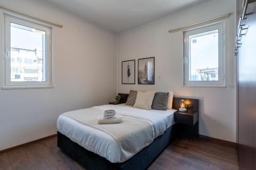 a bedroom with a large bed with two windows at Harbor Apartments in Larnaca in Larnaka