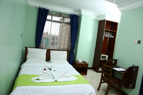 a bedroom with a bed with two towels on it at Sandton City Hotel in Nairobi