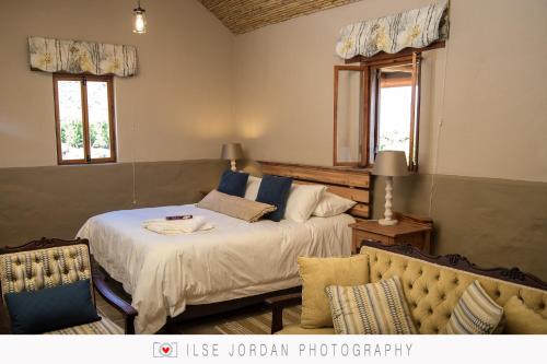 a bedroom with two beds and a couch at KARUSA’s Farm Cottage in Oudtshoorn