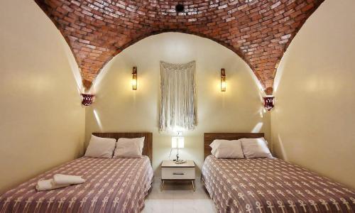 two beds in a bedroom with a brick wall at West Bank luxury villa in Luxor
