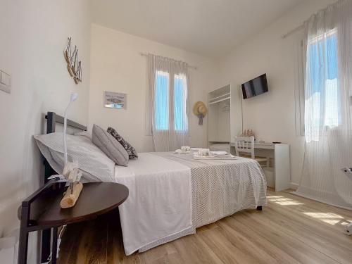 a white bedroom with a bed and a table at La Marina - Rooms In Stintino by Host Hero in Stintino