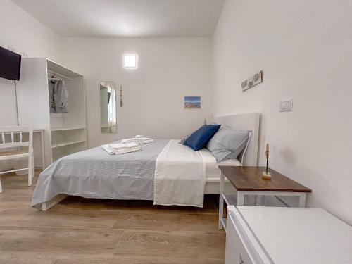 a white bedroom with a bed and a table at La Marina - Rooms In Stintino by Host Hero in Stintino