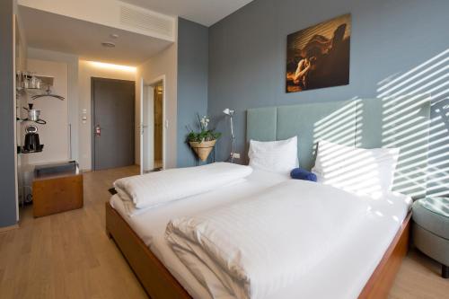 1 dormitorio con 1 cama grande con sábanas blancas en Hotel Lava Inn - 24 h Check-In - Nähe LKH, Landeskrankenhaus, Feldbach en Feldbach