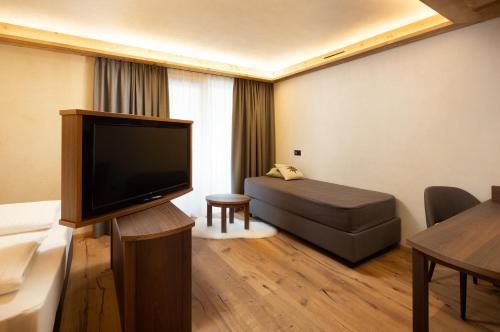 a living room with a couch and a flat screen tv at Camino Rustic Chic Hotel in Livigno