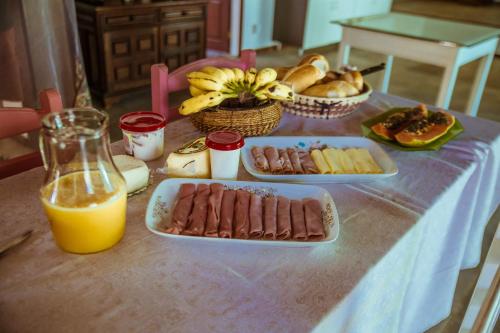 a table with plates of food and a glass of orange juice at Vila Palmar Hospedagem in Vassouras