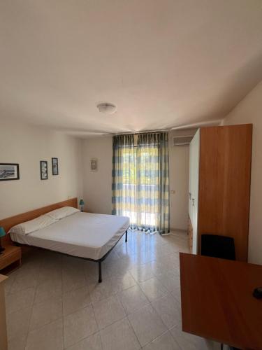um quarto com uma cama e uma grande janela em Residence Verde Pineta em Principina a Mare