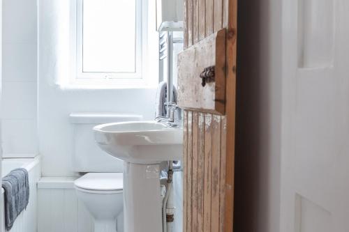 a bathroom with a sink and a toilet and a window at Cosy Beachside Cottage in Bigbury