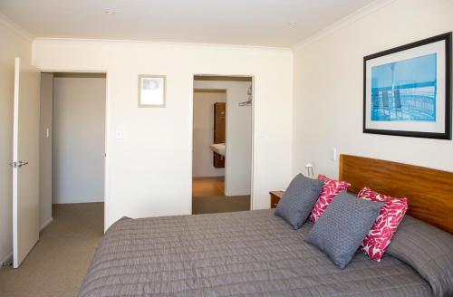 ein Schlafzimmer mit einem Bett mit Kissen darauf in der Unterkunft The Reef Beachfront Apartments in Mount Maunganui