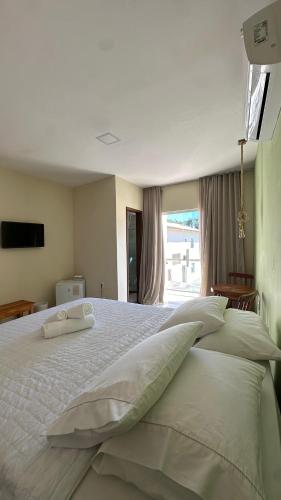 a bedroom with a large bed with pillows and a window at Humaita Pousada in Itacaré