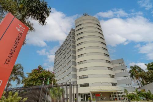 a tall white building with a tree at Transamerica Fit Villa Lobos in Sao Paulo