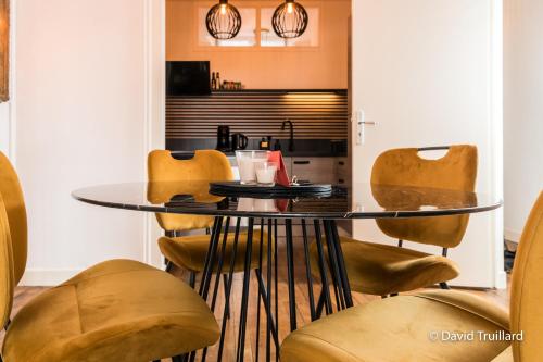 a dining room with a glass table and chairs at Suites Mana - MAHANA avec VUE SUPERBE sur la Place DUCALE et Parking privé inclus in Charleville-Mézières