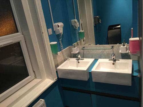 La salle de bains est pourvue de 2 lavabos et d'un miroir. dans l'établissement Book A Bed Hostels, à Londres