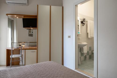 a bedroom with a bed and a bathroom with a kitchen at Hotel Continental in Caorle