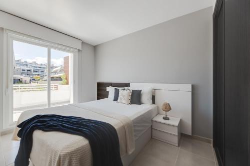 une chambre blanche avec un grand lit et une fenêtre dans l'établissement Nova SuperBeach 38, à Gran Alacant