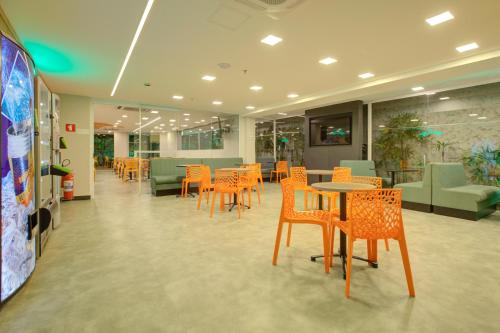 eine Cafeteria mit orangenen Stühlen, Tischen und Stühlen in der Unterkunft Transamerica Fit Villa Lobos in São Paulo