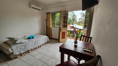 1 dormitorio con cama, mesa y ventana en Iguazu Hojas Verdes en Puerto Iguazú