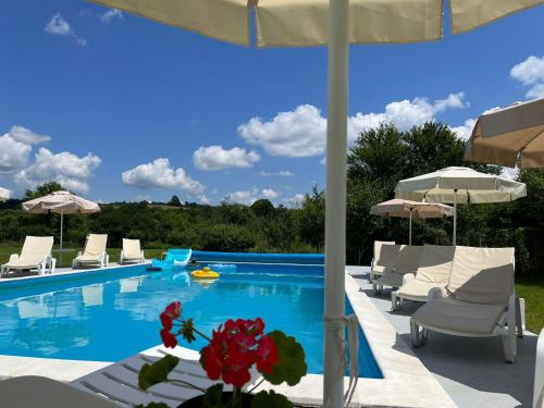 a swimming pool with white chairs and umbrellas at Guest House Gerasimovi in Elena