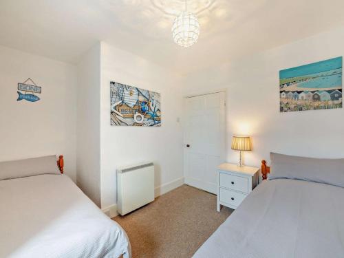 Un dormitorio con dos camas y una mesa con lámpara. en Harbour Stroll Seahouses. Close to the harbour., en Seahouses