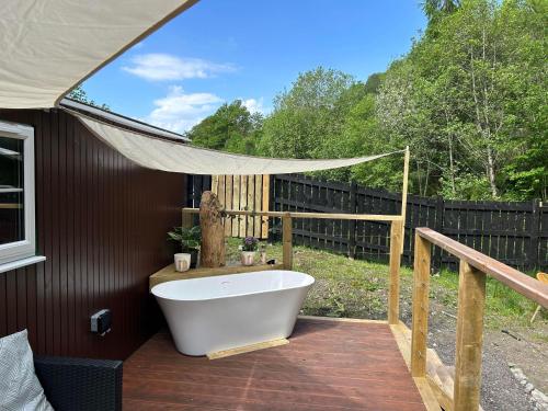 a bath tub sitting on a deck in a backyard at Appin Holiday Homes -Caravans, Lodges, Shepherds Hut and Train Carriage stays in Appin