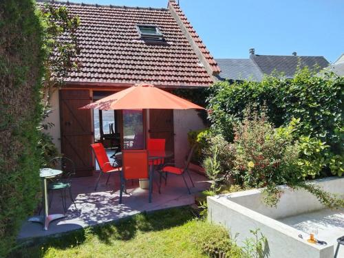 un patio avec une table, des chaises et un parasol dans l'établissement Maison de l'épinette au calme en bord de mer, à Cayeux-sur-Mer