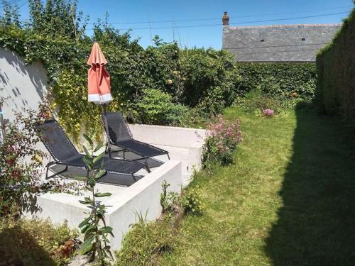 une paire de chaises avec un parasol dans un jardin dans l'établissement Maison de l'épinette au calme en bord de mer, à Cayeux-sur-Mer