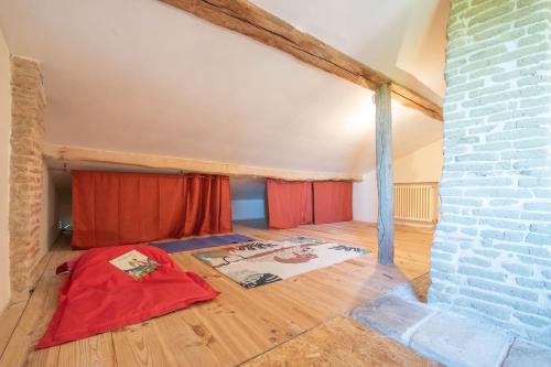 une chambre mansardée avec des rideaux rouges et un mur de briques dans l'établissement Gite Mondurausse - avec piscine et vue sur la vallée, à La Salvetat-Belmontet