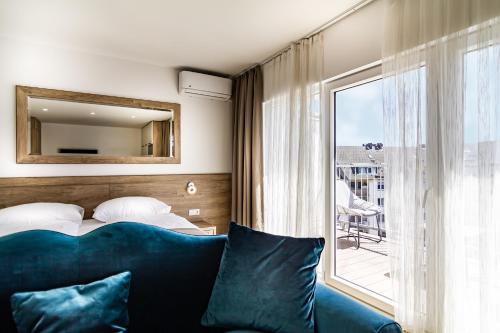a bedroom with a blue couch and a bed and a window at Sleep Inn Düsseldorf in Düsseldorf