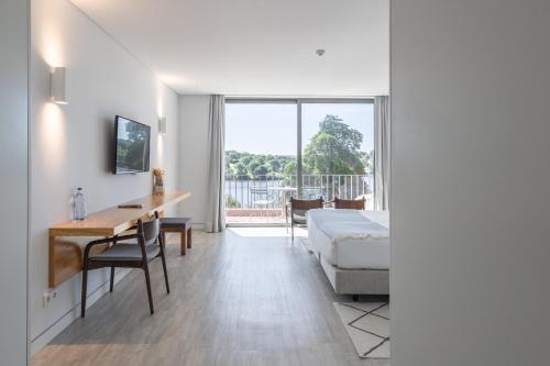 a bedroom with a bed and a desk and a bed and a table at Vale do Gaio Hotel in Torrão