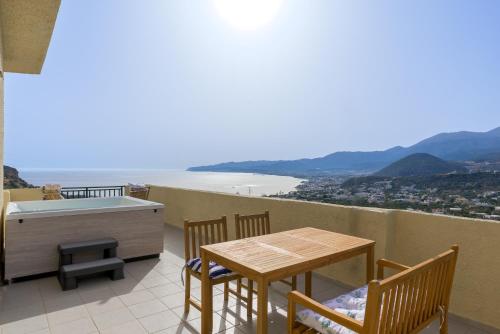 a balcony with a table and chairs and a bath tub at Blue Horizon Apartments in Stalida
