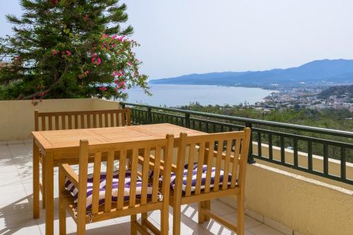 a wooden table and chairs on a balcony with a view at Blue Horizon Apartments in Stalida