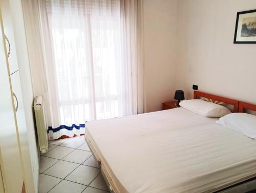 1 dormitorio con cama blanca y ventana en Fides Apartment, en Rosolina Mare