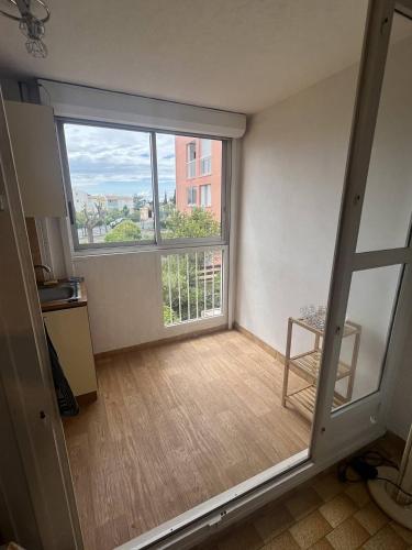 une pièce vide avec une grande fenêtre et une chaise dans l'établissement JULES VERNE Agréable studio cabine Mt St Martin proche port Cap d'Agde, au Cap d'Agde