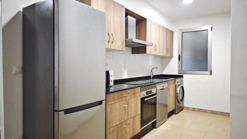 a kitchen with a stainless steel refrigerator and wooden cabinets at Desconectaengalicia Carlos Casas Playa Silgar in Sanxenxo