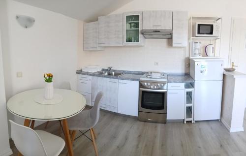 a kitchen with white cabinets and a table and a sink at Rooms and Apartments Riviera in Rab